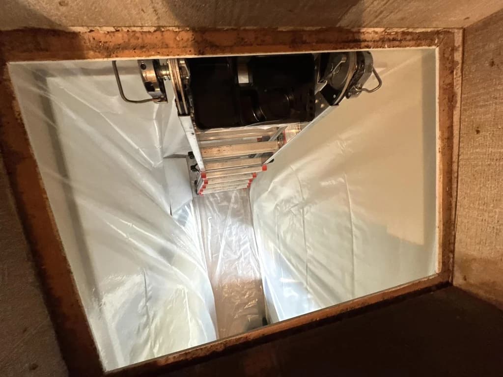View down a Twinsburg attic opening toward a ladder and plastic-lined access route