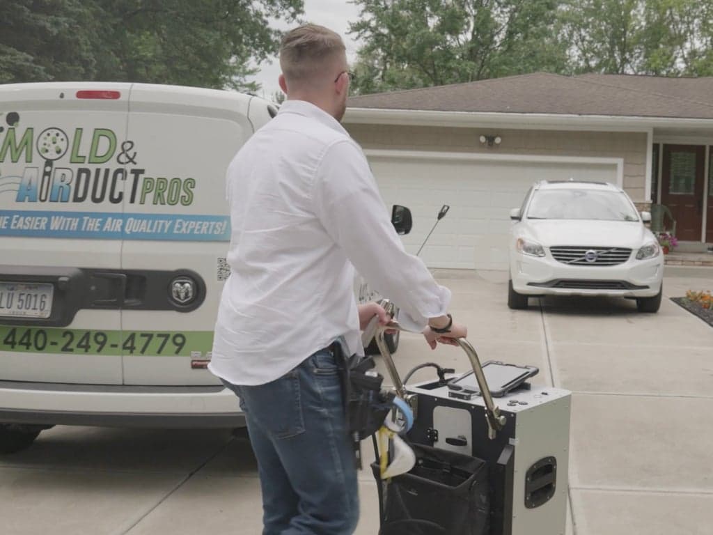 Mold and Air Duct Pros inspector Mark arriving at a Northeast Ohio home with inspection equipment beside a branded service van