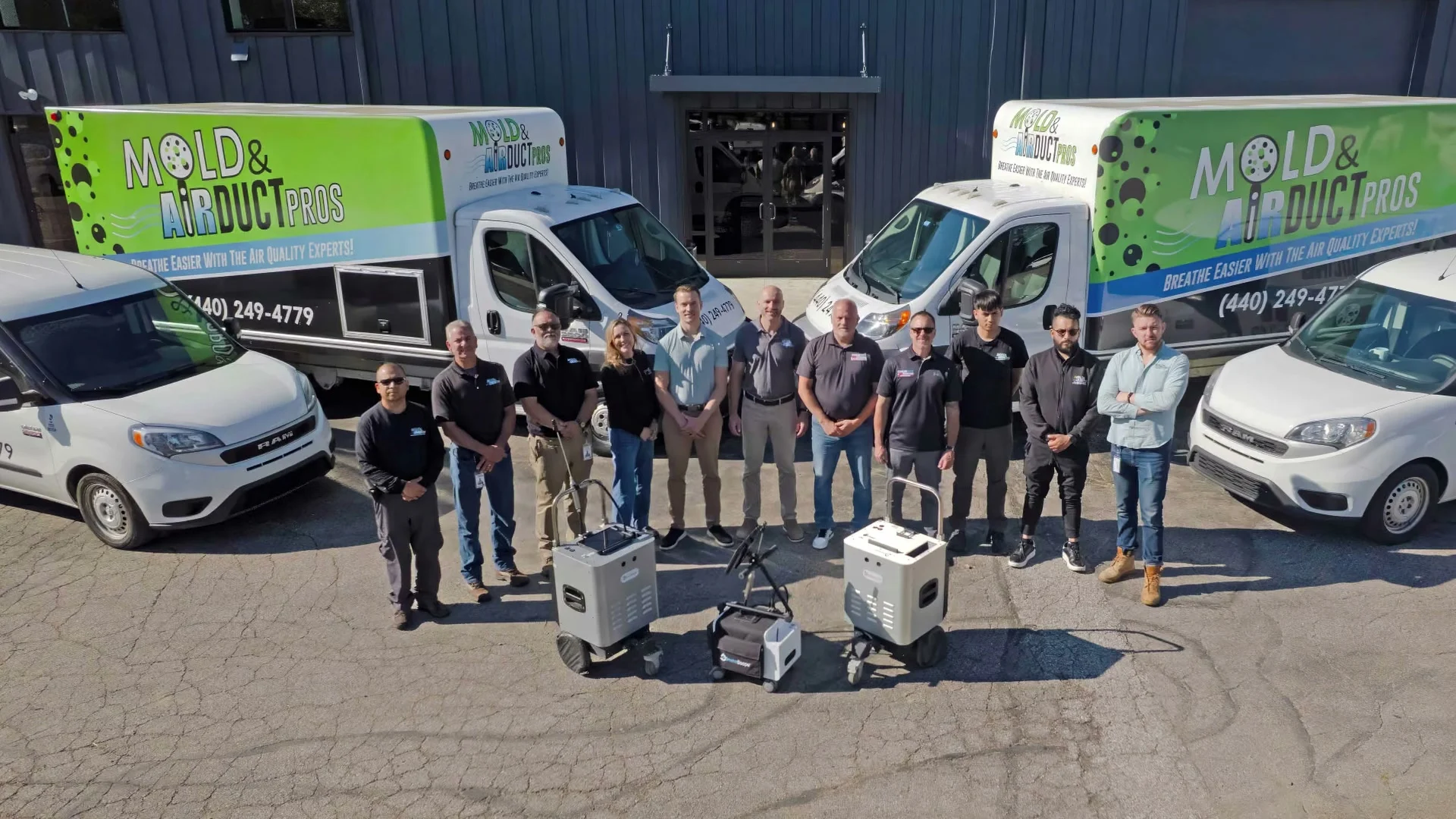 The Mold and Air Duct Pros team standing with their service vans and air-quality equipment outside the company building