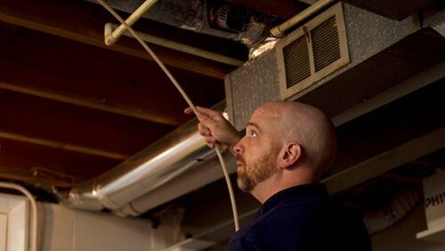 A team member from Mold and Air Duct Pros inspecting ventilation in a basement before mold remediation