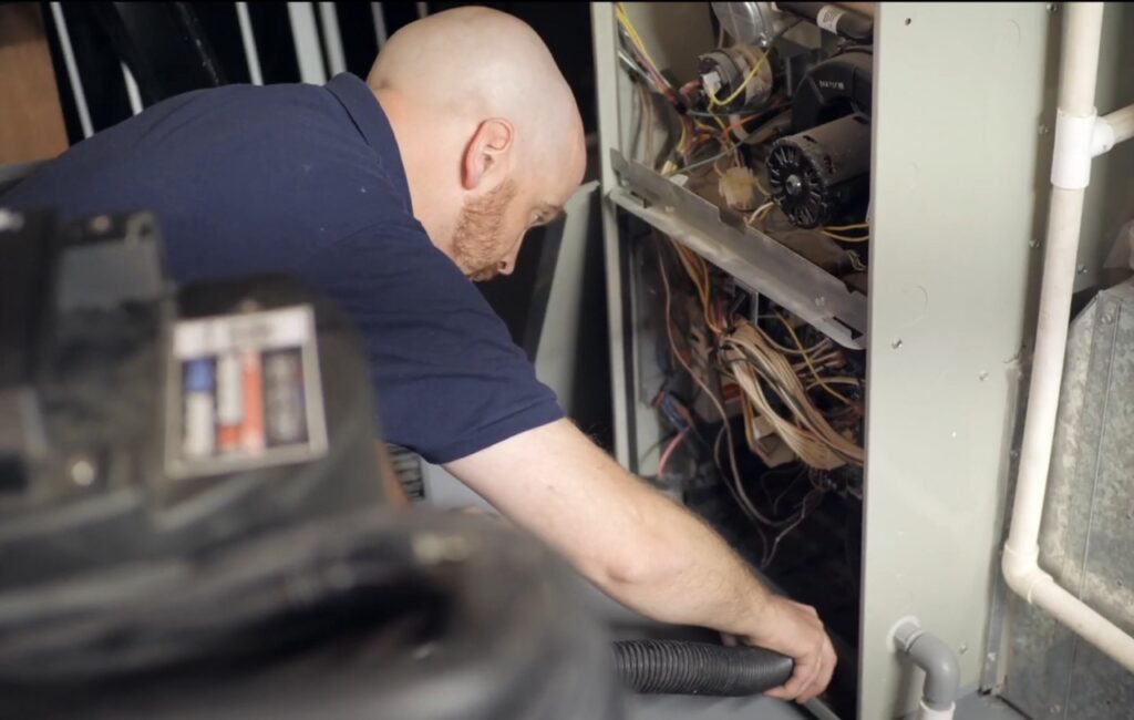 Mold and Air Duct Pros vacuums out the furnace.