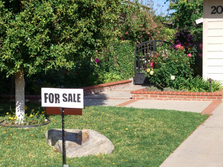 A “For Sale” sign outside of a suburban home.