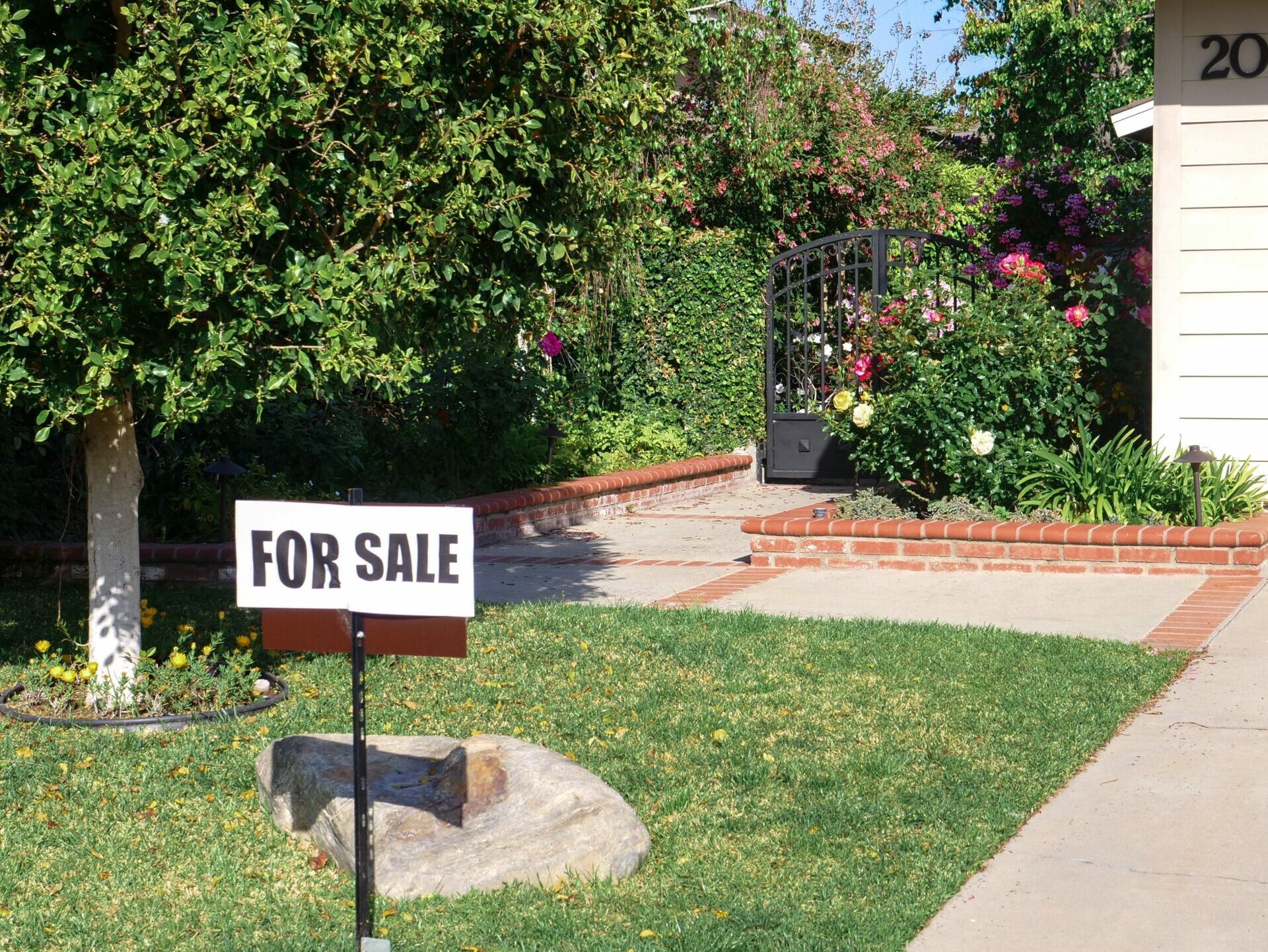 A “For Sale” sign outside of a suburban home.
