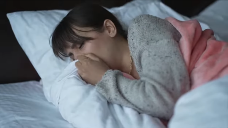 A sick woman in bed coughing